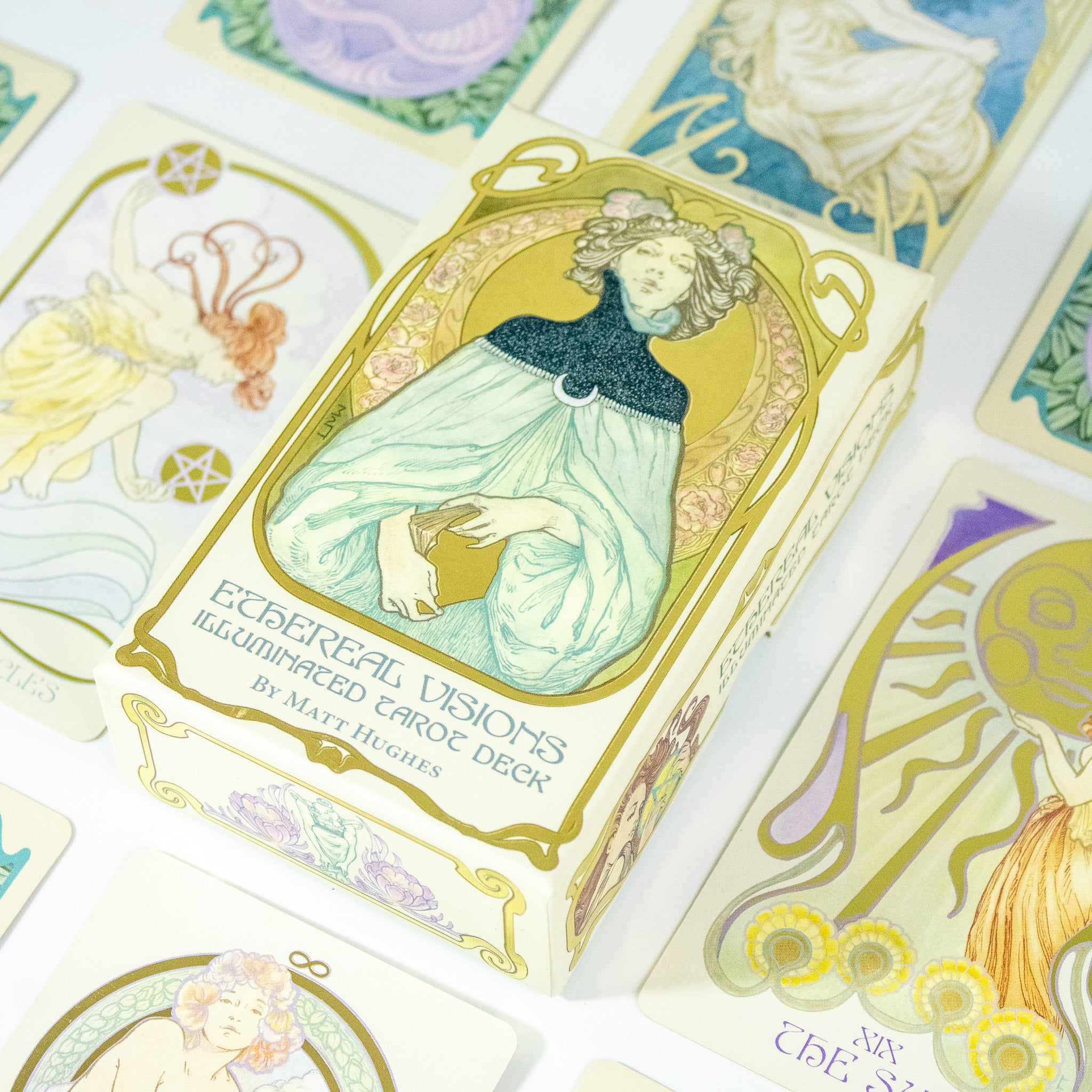 Ethereal Visions Tarot deck box. A woman dressed in blue holds a tattered book. Other cards are around the box.