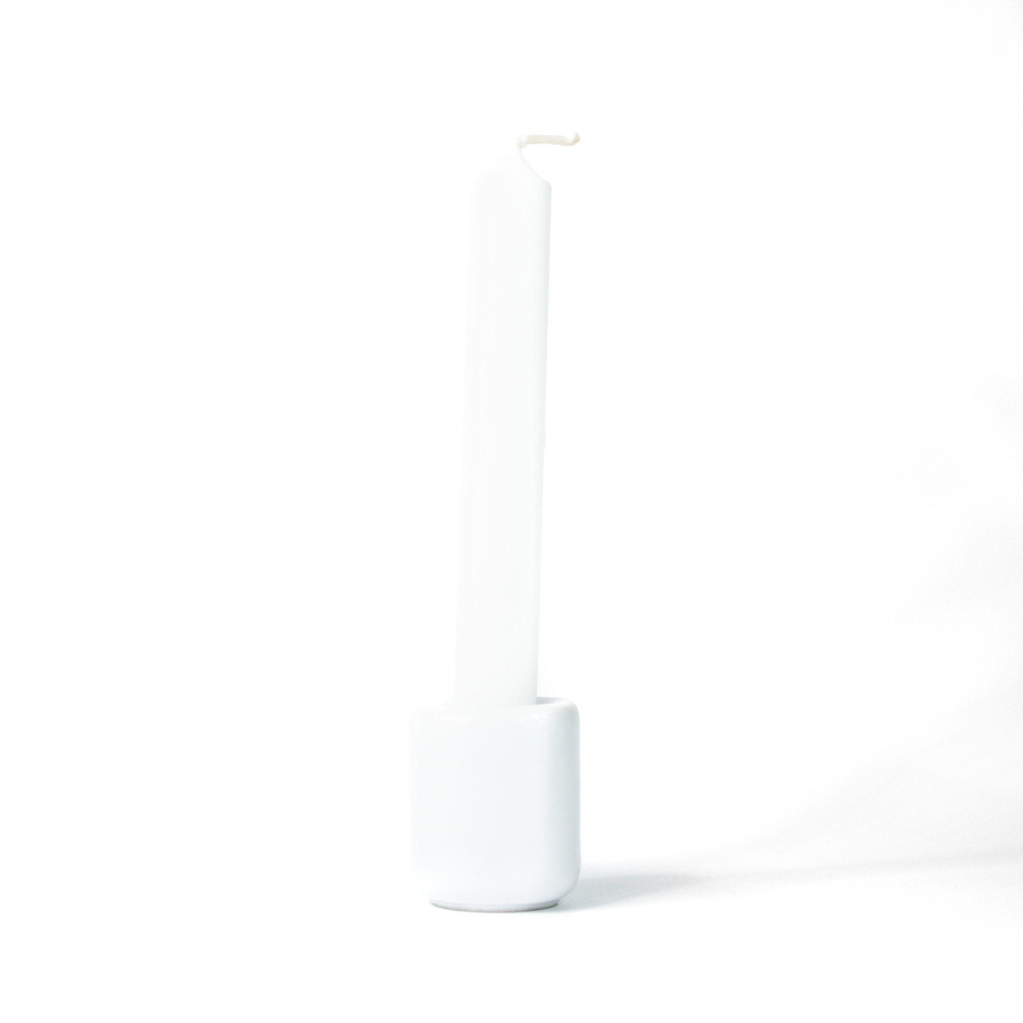 White chime candle for spellwork and intention setting, set in a white ceramic candle holder with white background.