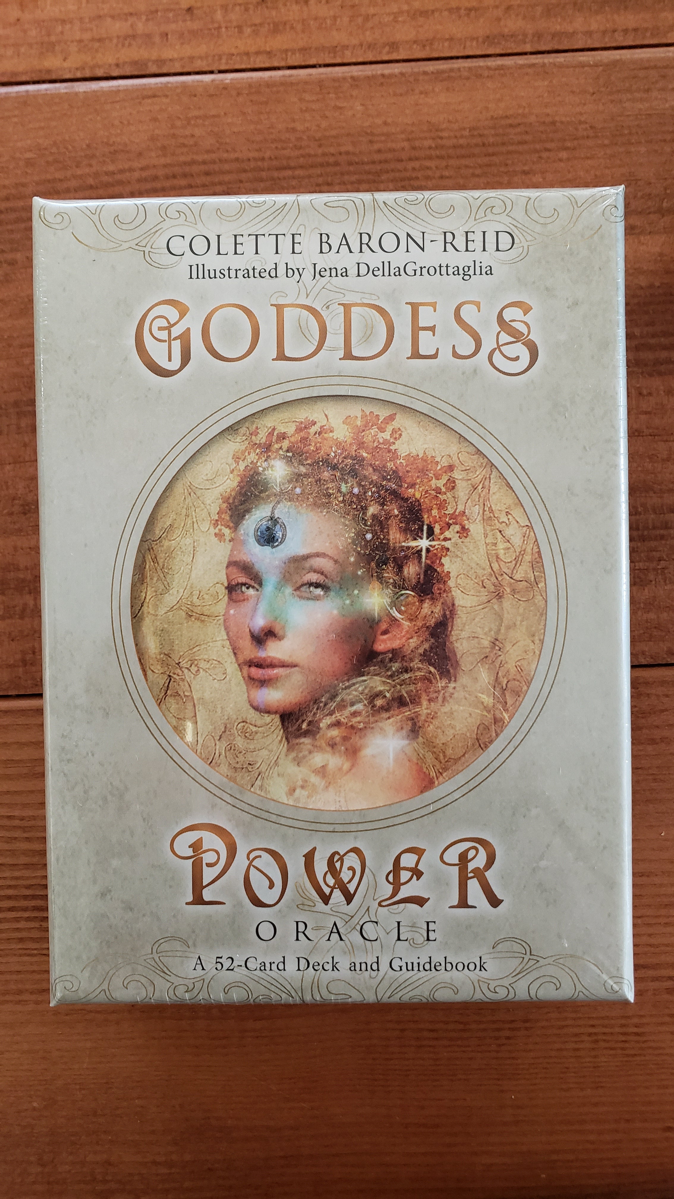 Box of the Goddess Power Oracle Deck by Colette Baron Reid. Box is tan with a woman shown surrounded by gold and stars in the center. 