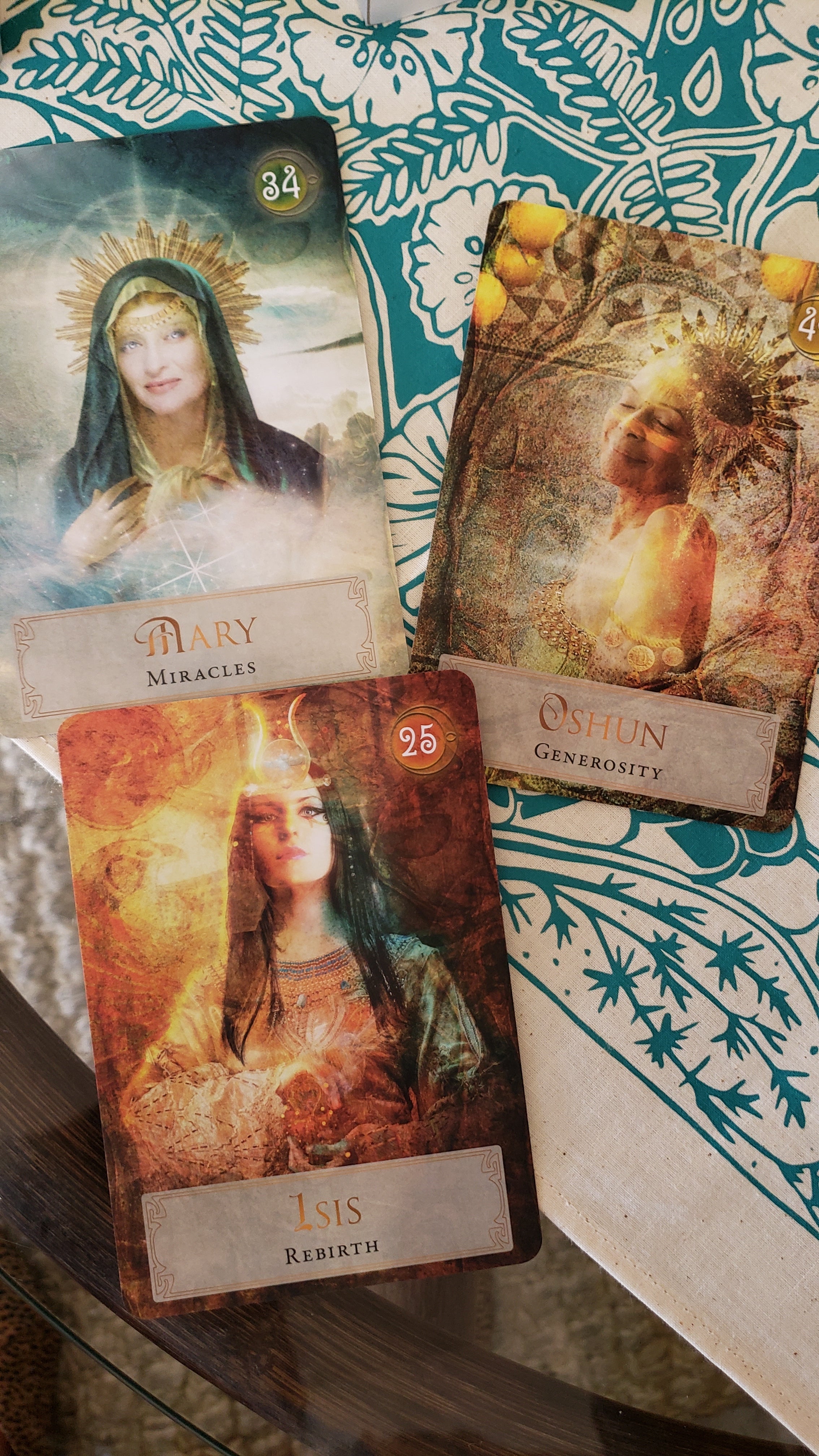 The Isis, Oshun and Mary cards from the Goddess Power Oracle deck are shown on a teal and beige altar cloth