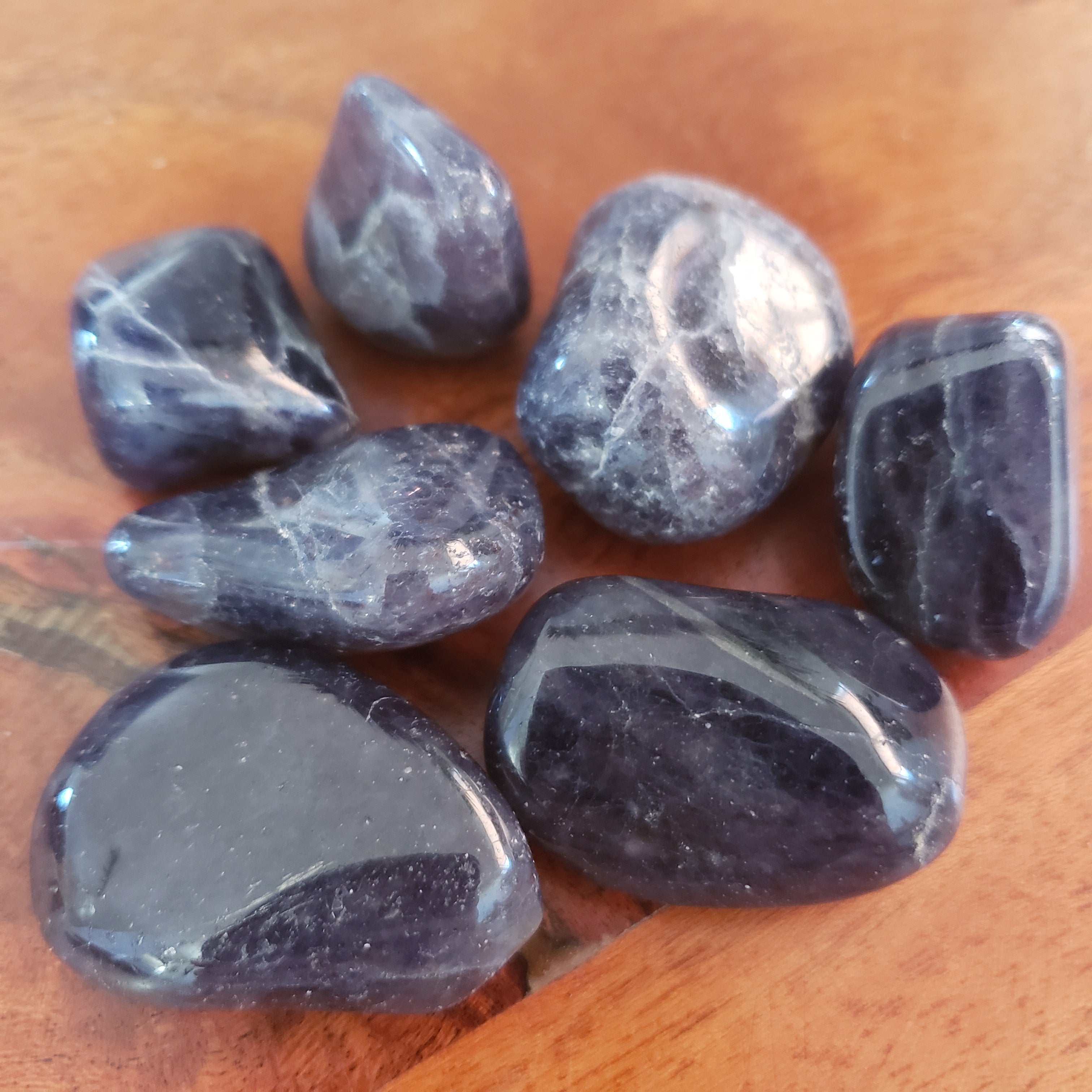 Close up of deep blue tumbled iolite pocket stones on wooden background